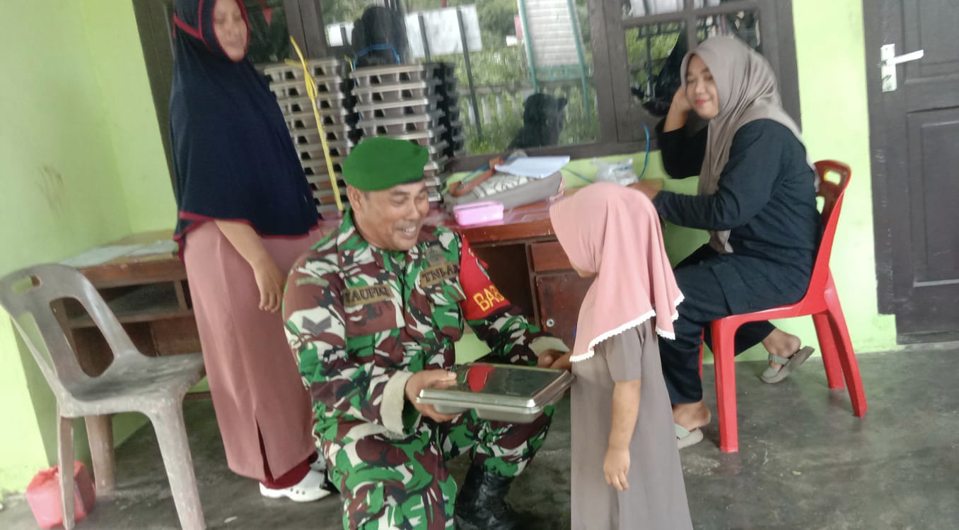 Dukung Program Pemerintah, Babinsa Koramil 01/Sukajaya Dampingi Pembagian Makanan Bergizi
